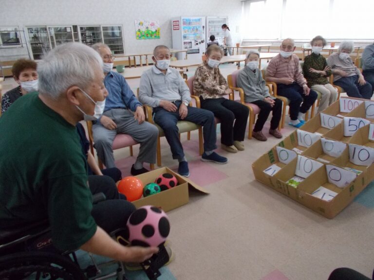 介護施設の共用スペースでボール投げゲームなどのレクリエーション活動を行う高齢者たちの様子